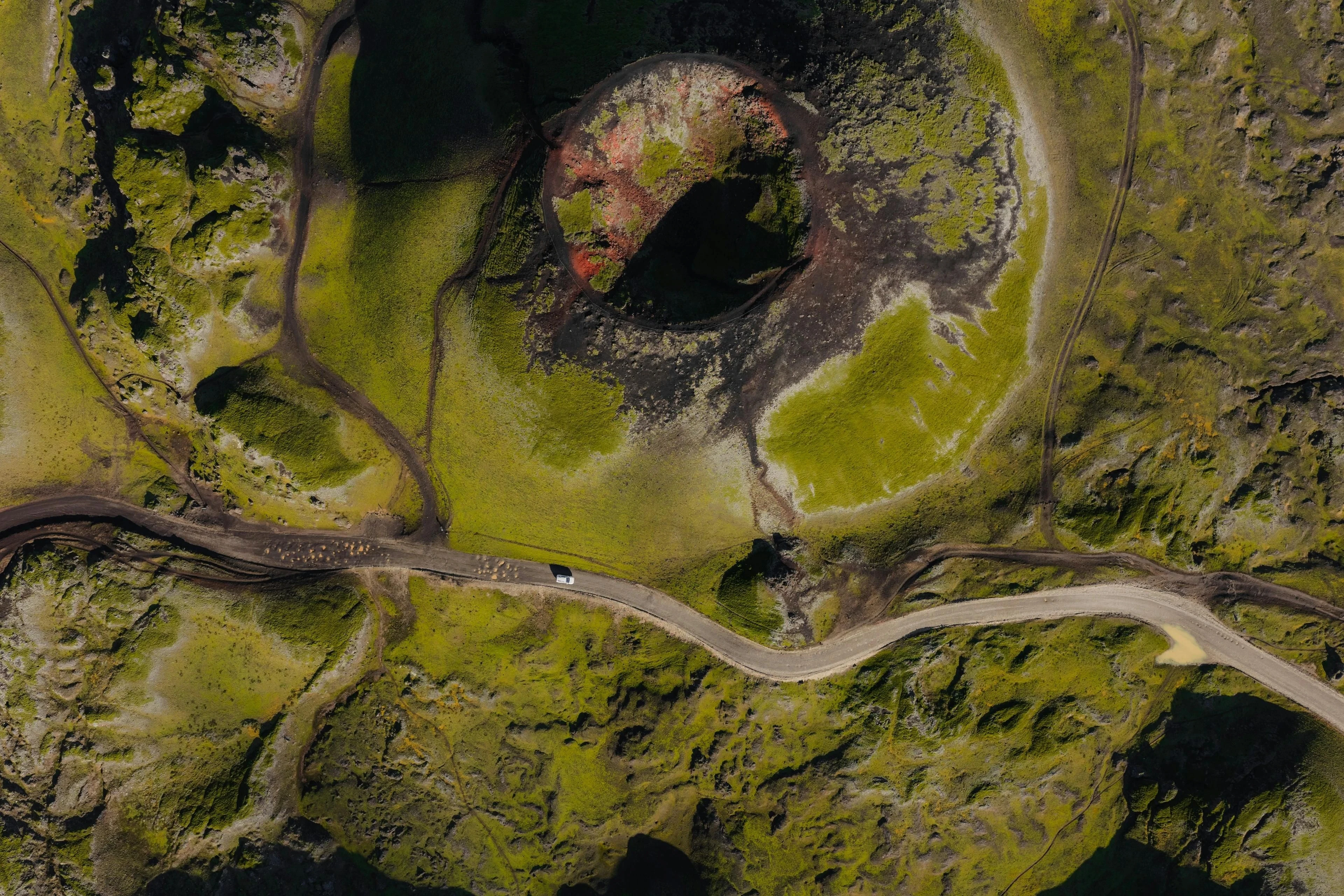 Aerial view of moss-covered volcanic ground surrounding a crater.