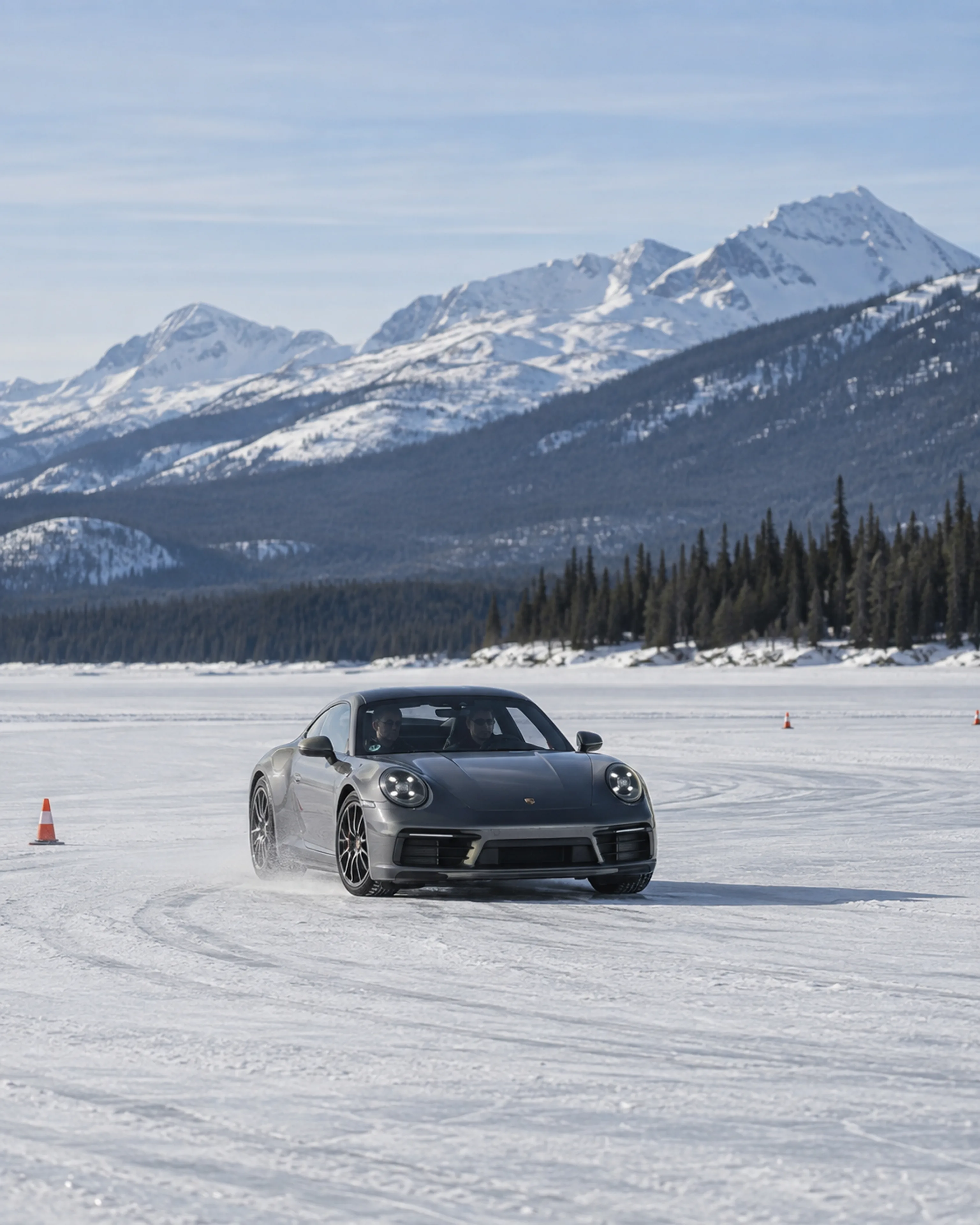 A graphite sports coupe practises a controlled corner between markers on a frozen lake.