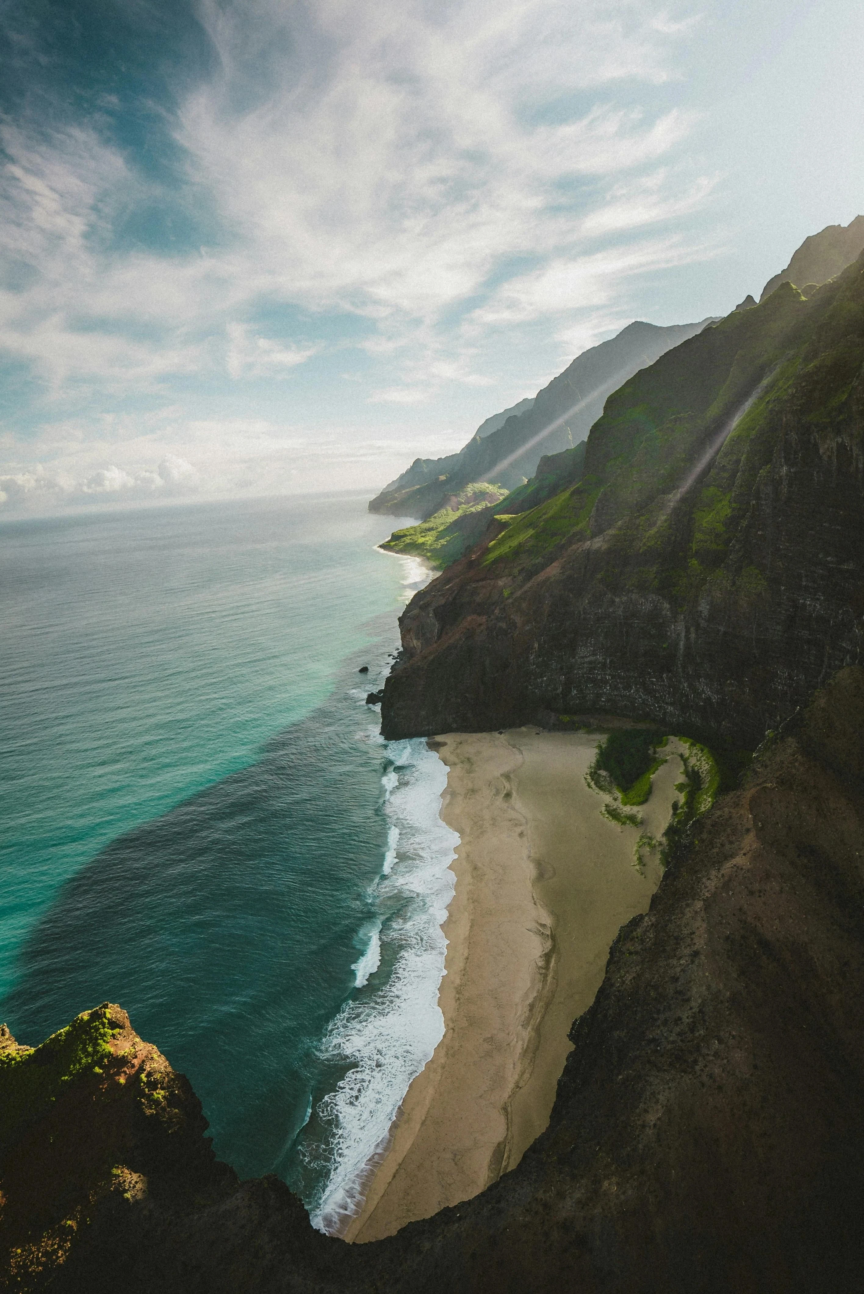 Steep green coastal cliffs rise above the ocean.