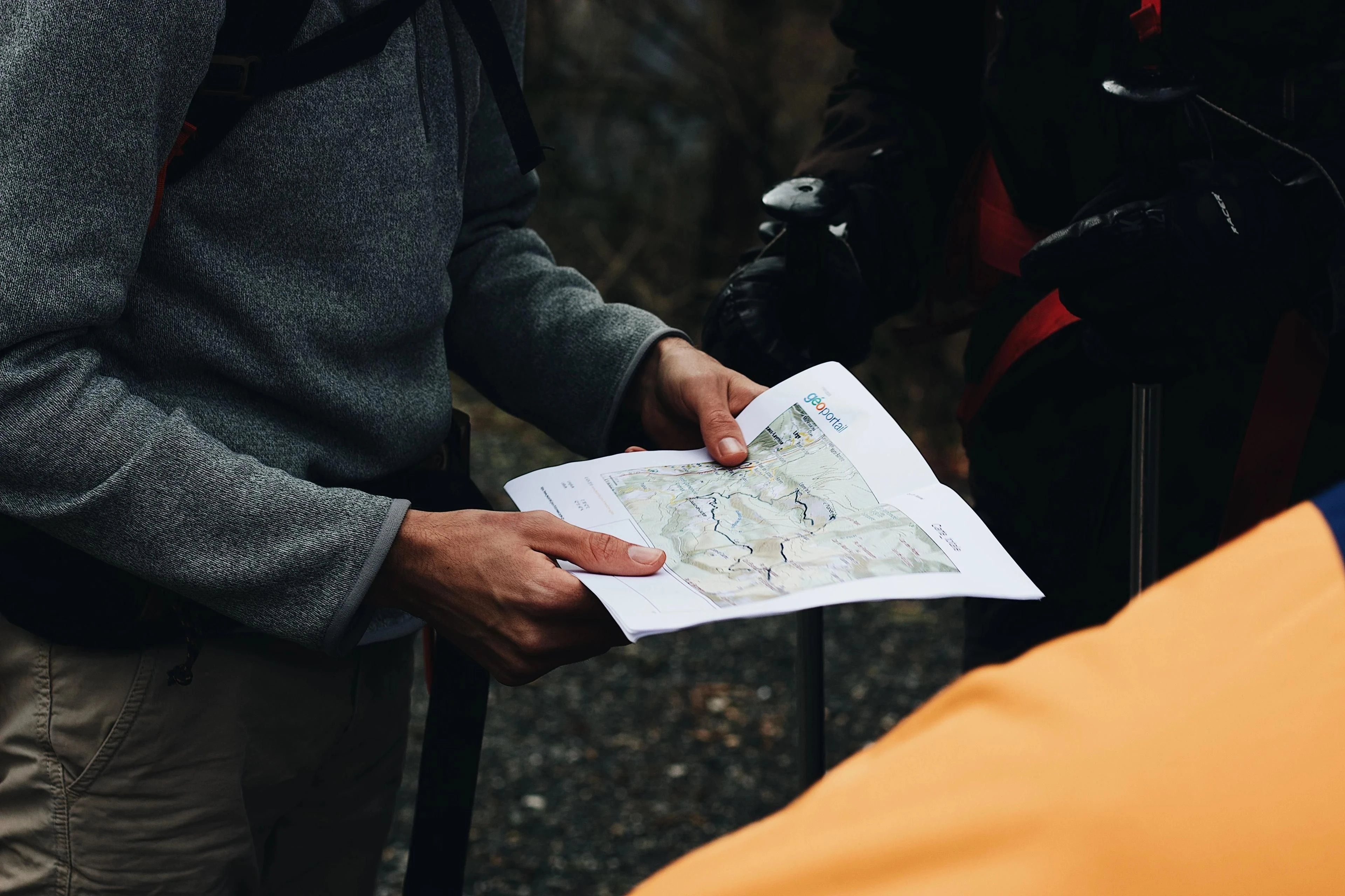 A small outdoor group studies a printed topographic route map beside packed equipment.