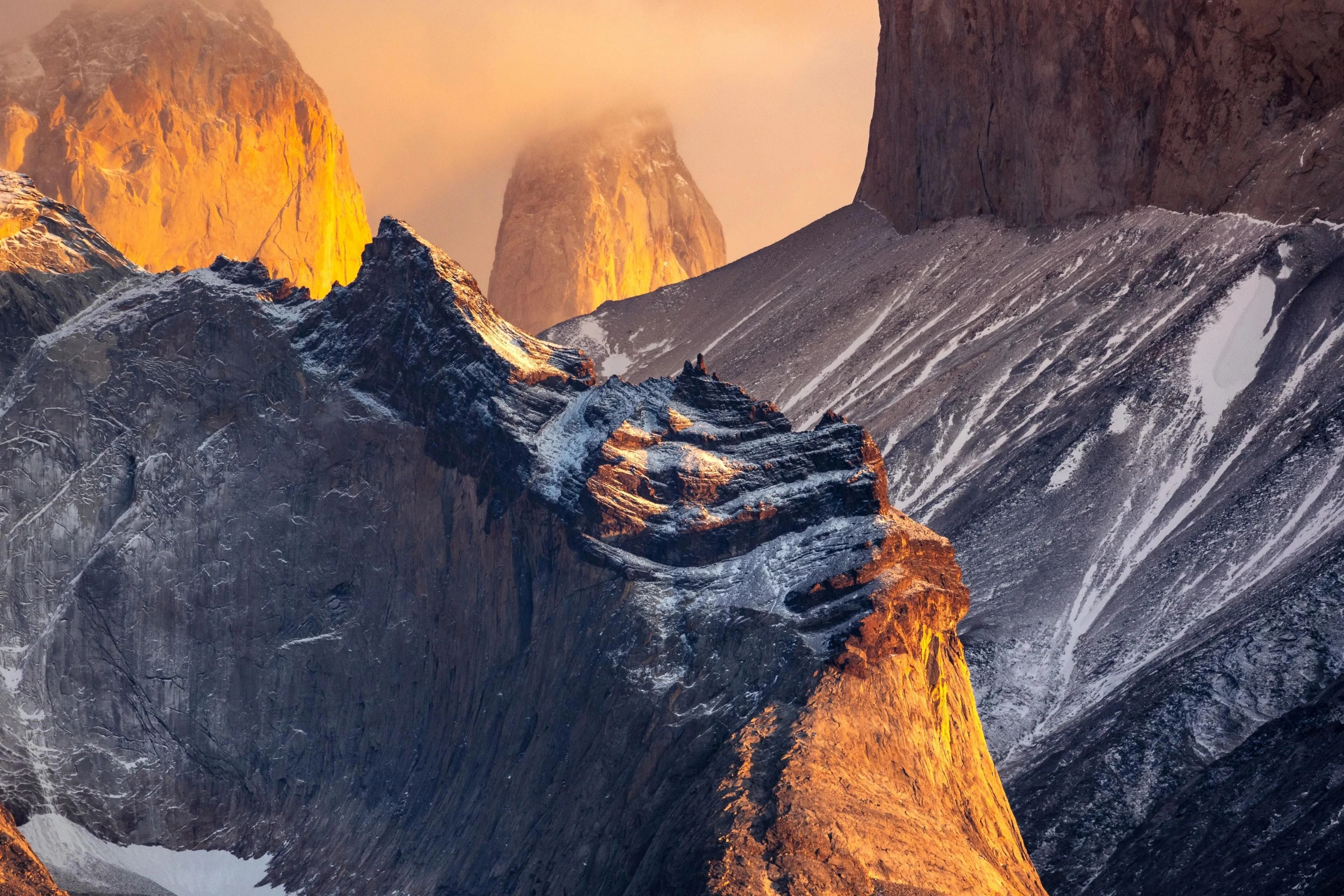 Low sunlight catches granite towers rising through clouds above shadowed ridges.